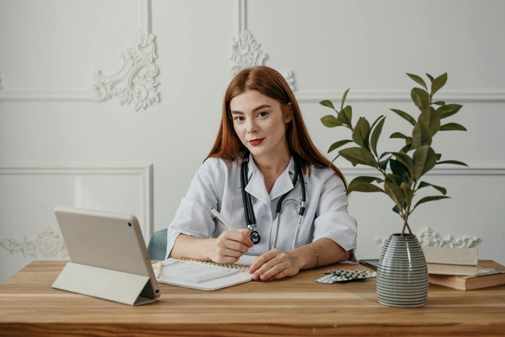 Young female doctor writing notes on a tablet in a modern office setting.